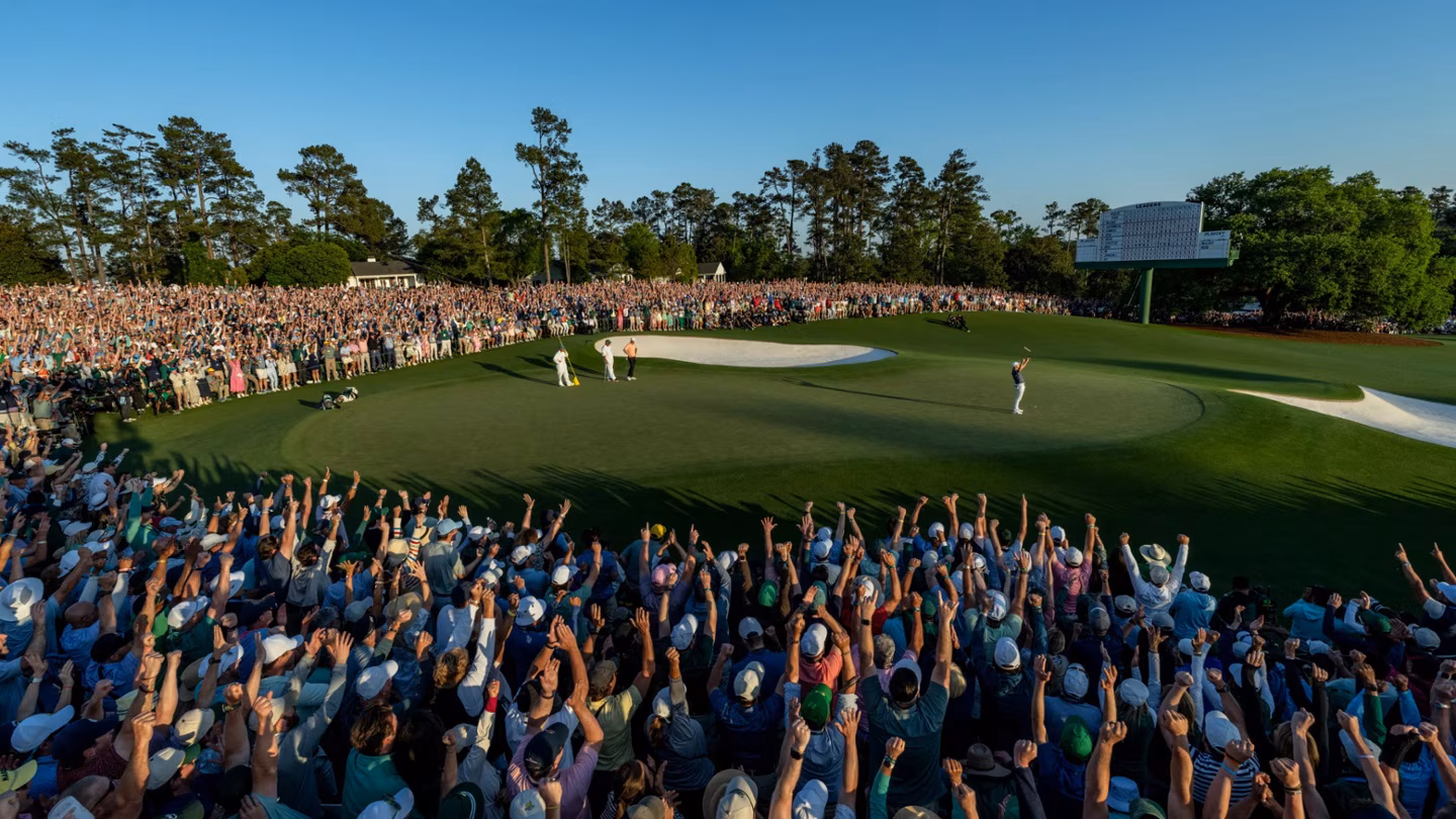 Patrons crowd the 18th green at Augusta in golden evening light